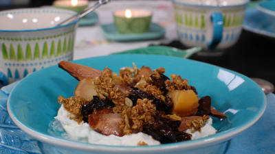 Portion med långbakad frukt och mysli på yogurt.