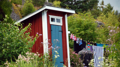 Ett rött utedass med ett byksnöre med kläder som hänger på tork intill.