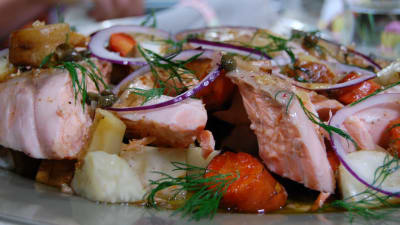 En portion rotsaker med ugnsbakad lax toppad med dill, rödlöksringar och kapris.