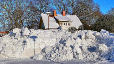 Stor snöhög framför ett hus