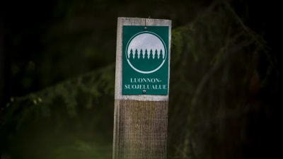 En skylt med texten "Luonnonsuojelualue" (naturskyddsområde).
