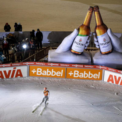Severin Freund bromsar in framför två stora ölreklamflaskor.