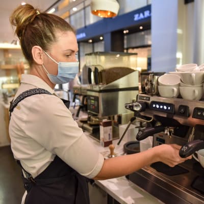 Försäljare på ett kafe jobbar med en kaffemaskin. 
