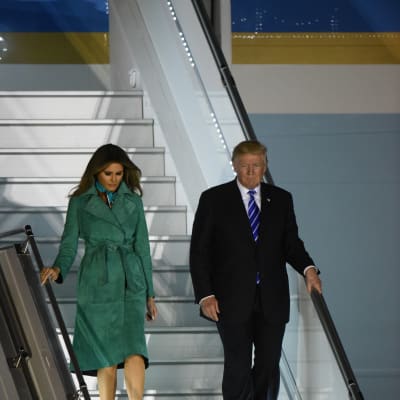 USA:s president Donald Trump går ner för ett flygplans trappor tillsammans med frun Melania Trump.