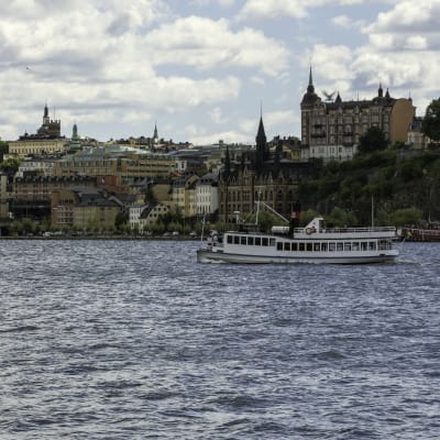 Vy över stadsdelen Södermalm i Stockholm, med Riddarfjärden och en båt i förgrunden.