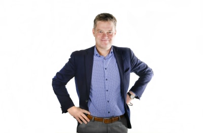 En man i kostym poserar framför kameran. 