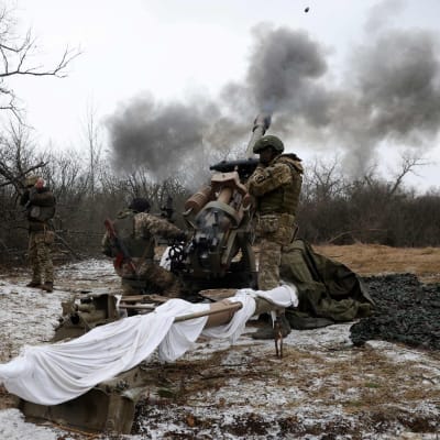 Ukrainska soldater avfyrar en L119-haubits mot Ryssland ute i terrängen. 