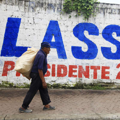 En man går förbi en väggmålning där det står: Lasso presidente 2017. Ecuador väljer ny president 2.4.2017.