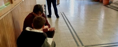 En lärare hjälper en pojke med läxan på en bänk i korridoren i en skola i Budapest.