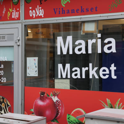Elintarvikekaupan näyteikkuna, jossa tekstinä Maria Market ja punapohjaiset teippaukset.