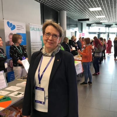 Varhan strategiajohtaja Leena Setälä seisoo messujen esittelypöydän edustalla.