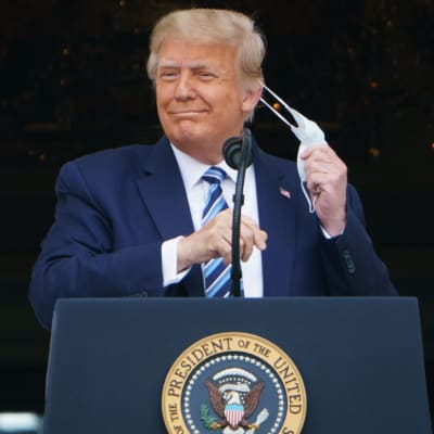 Donald Trump tar av sig sin ansiktsmask innan han talar till anhängare den 10 oktober 2020.
