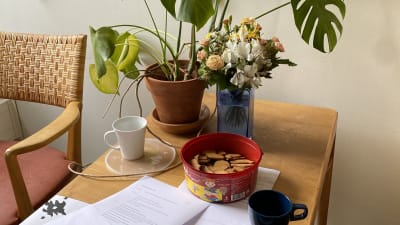 Ett bord med några kaffekoppar, en pepparkaksburk och blommor.