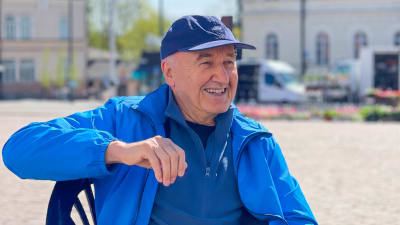 En glad, äldre man sitter på torgcafé i Lovisa. 