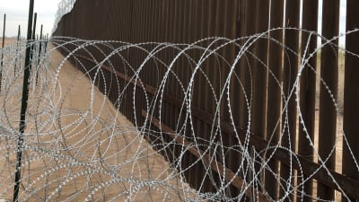 Taggtråd i flera lager runt ett gränsstaket mellan USA och Mexiko