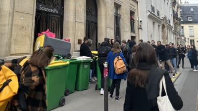 Folk har samlats utanför en ingång till ett hus i Paris.