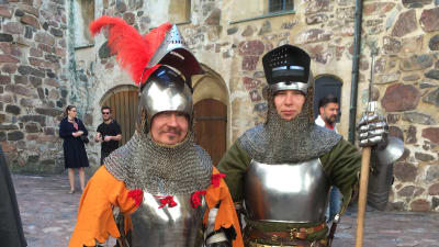 Två skådespelare står i soldatkostym från medeltiden. 