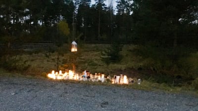 Många ljus brinner på marken vid en plankorsning till minne för fyra personer som avled i en olycka i slutet av oktober 2017.