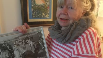 Journalisten Leena Larjonko poserar med fotografi över Alfred Hitchcocks besök i Finland