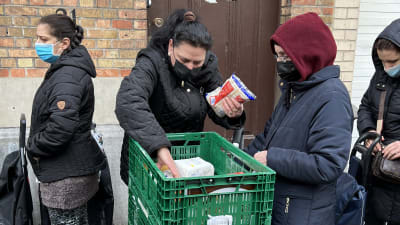 En kvinnar plockar upp livsmedel från en korg utanför en matutdelning i Bryssel
