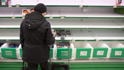 En person står framför en nästan tom butikshylla.