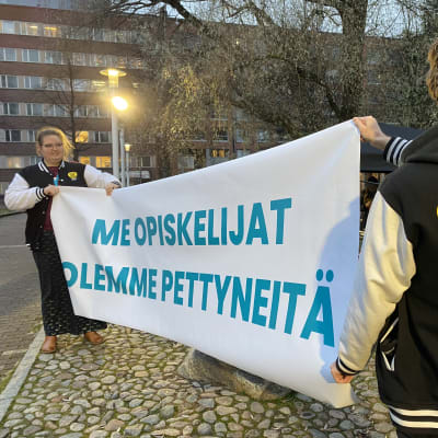Yliopiston opiskelijat osoittavat mieltä leikkauksia vastaan kylteillä. 