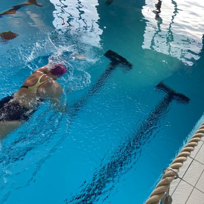 En person simmar i en simbassäng.