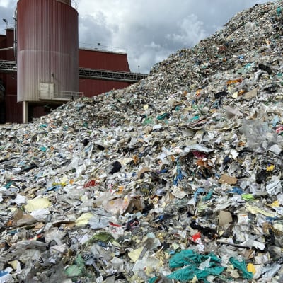 Kuvassa on Kaipolan entisen paperitehtaan pihamaalla seisova iso kasa silputtua muovia. Kierrätysmuovi on menossa tehtaan voimalan kattilaan poltettavaksi