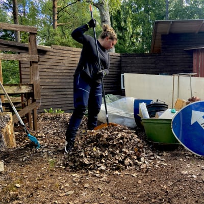 En kvinna som krattar löv.
