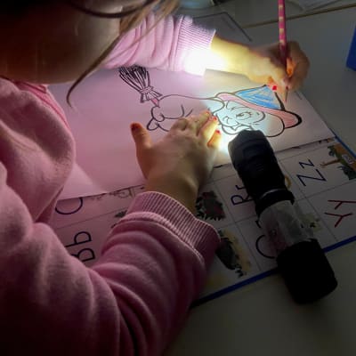 Lapsi piirtää taskulampun valossa.
