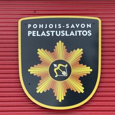 Punaisella seinällä on Pohjois-Savon pelastuslaitoksen merkki.
