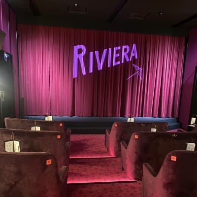 Elokuvateatteri Rivieran näyttämö. Sivuilla sohvia, edessä näyttämö ja Rivieran logo.