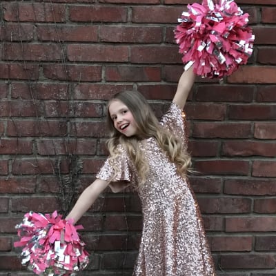 Ida poserar framför kameran med pompoms i händerna.
