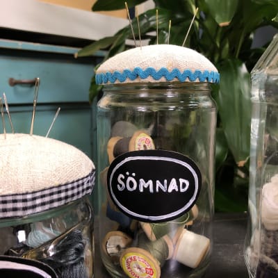 Burk med texten sömnad fylld med trådrullar