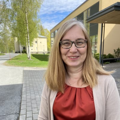 Nainen seisoo koulun pihalla.