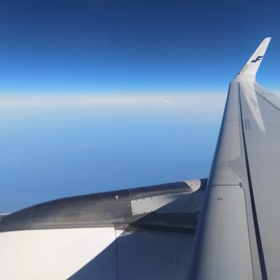 Bild tagen från ett flygplan, blå himmel i bakgrunden med vingen synlig.