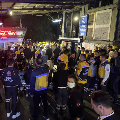 Räddningsarbetare och gruvarbetare sår samlade utanför en gruva i Turkiet.