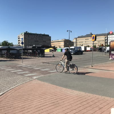 Pyöräilijä lähestyy lainvastaisesti merkittyä pyörätien jatketta Joensuun keskustorin laidalla kesäpäivänä.