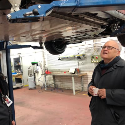 Turun ammatti-instituutin opettaja Joni Järvinen ja sähköautoilija katsovat sähköauton pohjaa.