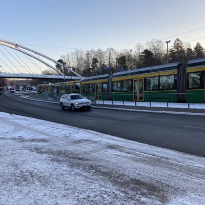 Två spårvagnar står stilla vid en hållplats en vintermorgon.