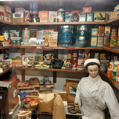 litet butikmuseum med docka föreställande ett butiksbiträde omgivet av butiksinredning och förpackningar