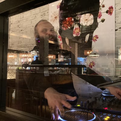 Iloinen mies dj-pöydän äärellä.