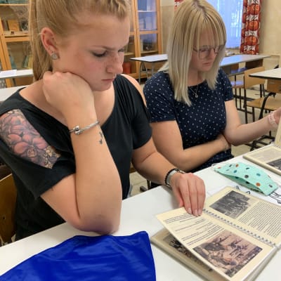 Kaksi tyttöä tutustuu koulumuseon luokkahuoneessa DDR:n aikaisiin koulukirjoihin.