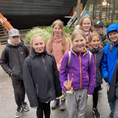 Kuvassa Langinkosken 5A-luokkalaisia luokkaretkellä Tykkimäen huvipuistossa Kouvolassa. Porukka hymyilee ja katsoo kameraan sateissa säässä.