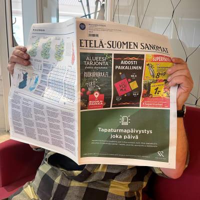Ihminen istuu sohvalla ja lukee Etelä-Suomen Sanomia.