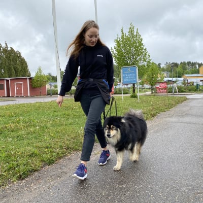 Ung tjej går med kopplad hund i samband med träningsuppdrag.