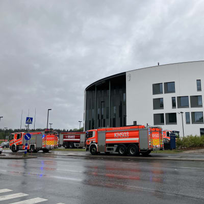 Palo- ja säiliöautoja Hämeenlinnan ympyränmallisen poliisiaseman pihalla sateisena päivänä.