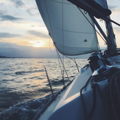 En segelbåt ute till havs i soluppgången.