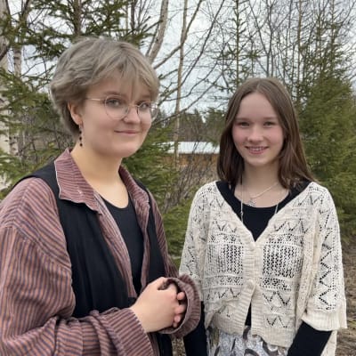 Emma Gahmberg ja Hilda Mustan potretti kaksi nuorta seisovat ja katsovat kameraan hymyillen.