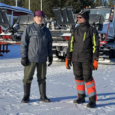 Eero Nikula ja Heikki Ranttila seisovat Inarin hiihtostadionin hiihtoladulla, taustalla latukone, 7.3.2023 Inari.